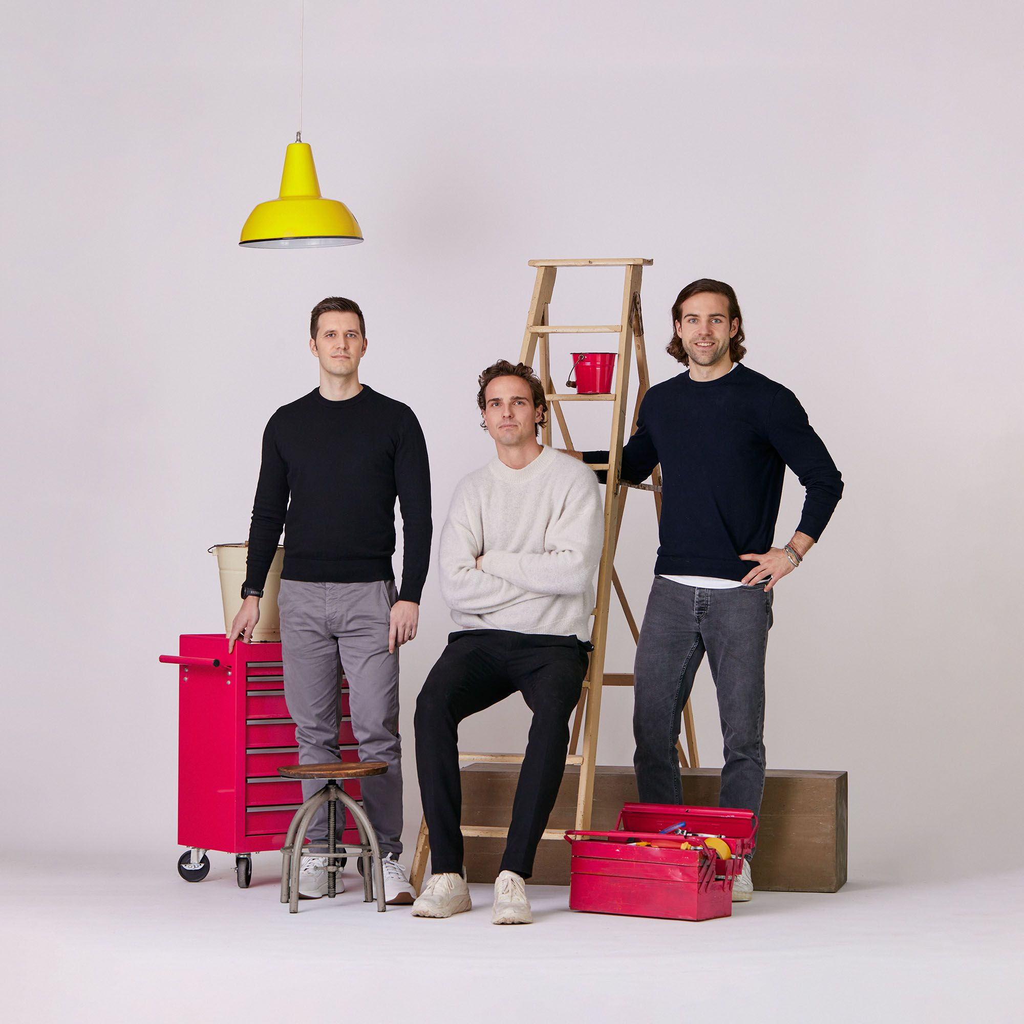 Three men standing in the middle of tool boxes.